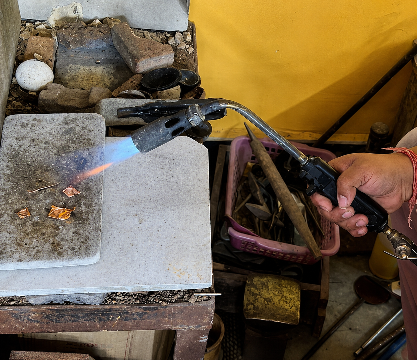 Craftsman using tweezers to position small metal beads on an engraved metal plate